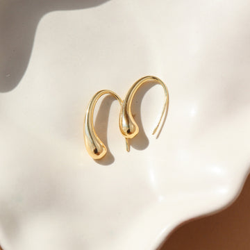 14k gold fill golden drop earrings laid on a white plate.