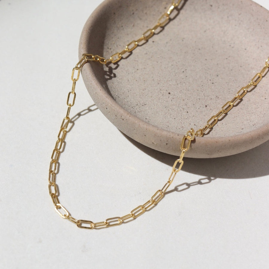 14k Gold fill Narrow Links chain laid on a white paper in the sunlight.