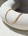 14k Gold Fill Gigi Necklace laid on a white plate in the sunlight.