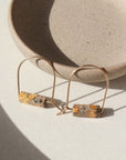 14k gold fill Leopard Skin Jasper Arches placed against a gray plate in the sunlight. 