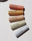 Solana Lip Balm Laid on a white paper in the sunlight.