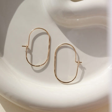 14k gold fill capsule hoops laid on a white plate. Handmade in Eau Claire, Wisconsin.