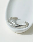 925 stacking cuff placed on a light gray plate, set in the sunlight.