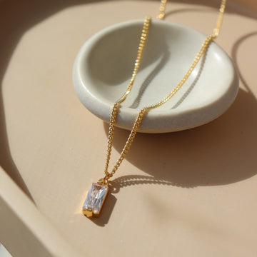 14k gold fill Euphoria Necklace, placed on a white plate on top of a peach colored plate in the sunlight. This necklace is hypoallergenic and nickel free. Handmade in Eau Claire, WI.