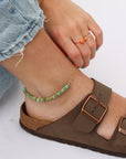A 14k gold fill beaded anklet with a chain link style chain shown on a model