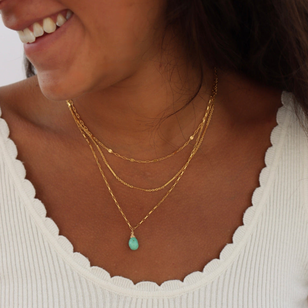 Model wearing Agave Necklace with a faceted sage green turquoise teardrop pendant on a reflective gold filled box chain, designed for everyday wear and layering.