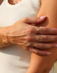 Close-up of a person wearing gold jewelry on a blurred background. Alex ring is a 14k gold fill chain link styled ring