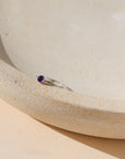 sterling silver band ring with 4mm amethyst stone on a light dish