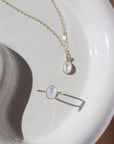 mother of pearl bezel pendant on a 14k gold fill delicate chain, and a mother of pearl ring, photographed on a white ceramic dish