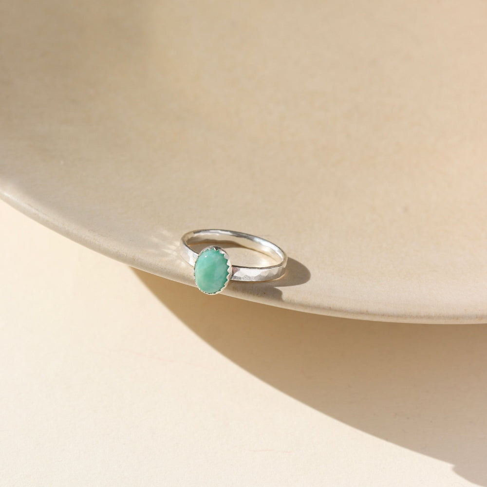 A 6x8mm amazonite gemstone set in a sterling silver serrated bezel. The ring is displayed on a cream dish.