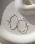 925 sterling silver capsule hoops laid on a white plate. Handmade in Eau Claire, Wisconsin.
