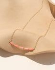 14k gold-filled necklace with five coral tube gemstones and serpentine beads, displayed on a tan dish.