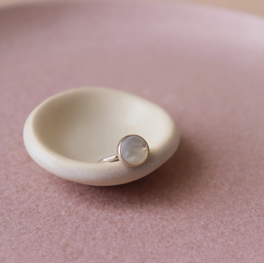 14k gold fill mother of pearl ring placed on a white plate in the sunlight.