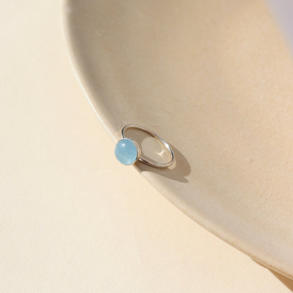 A sterling silver hammered gold band with a 8mm aquamarine gemstone set in a silver bezel.