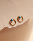 14k gold fill, circle hammered ear jacket that is paired with a 4mm turqouise stud, displayed on a cream backdrop in the sunlight