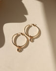 14k gold fill heart charm on large hoop earrings in the sunlight with shadows