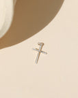 sterling silver handmade hammered cross charm on a light background