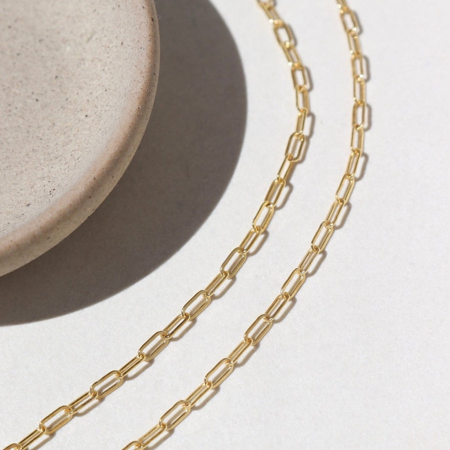 14k Gold fill Narrow Links chain laid on a white paper in the sunlight.