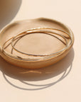 Fine Line Bangle in gold fill and sterling silver, hammered to a shine, shown stacked with other bracelets and worn solo for a minimalist look.