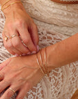 Fine Line Bangle in gold fill and sterling silver, hammered to a shine, shown stacked with other bracelets and worn solo for a minimalist look.