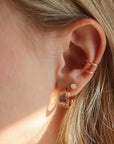 Close-up of Florence gold fill huggie earrings on a model styled