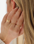 model wearing 14k gold fill textured ring with 14k gold fill hand chain and heart charmed ring