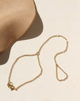 A 14k gold fill rolo hand chain with three margot pearls wire wrapped into the chain. The hand chain is displayed on a. cream back drop.