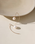 Delicate sterling silver half-moon earrings with smooth freshwater pearls set beneath a curved crescent design.