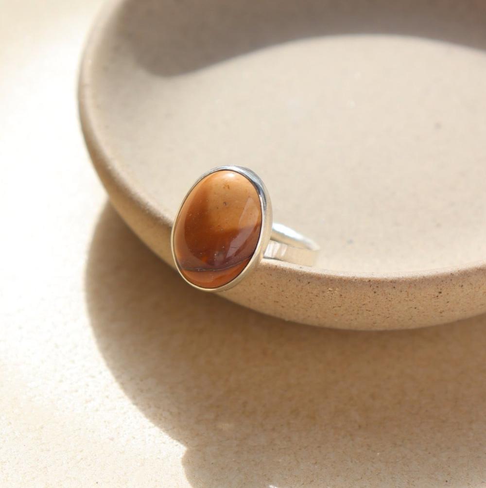 The Harvest Ring features a mookite gemstone encased in a pretty oval bezel, set within your choice of a textured 14k gold fill or sterling silver band.