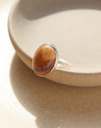 The Harvest Ring features a mookite gemstone encased in a pretty oval bezel, set within your choice of a textured 14k gold fill or sterling silver band.
