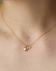 Model is wearing 14k gold fill puffy heart style charm with two gemstones on a gold chain, pictures on a ceramic dish