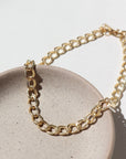 14k gold fill Alexandra anklet laid on a tan jewelry plate in the sunlight.