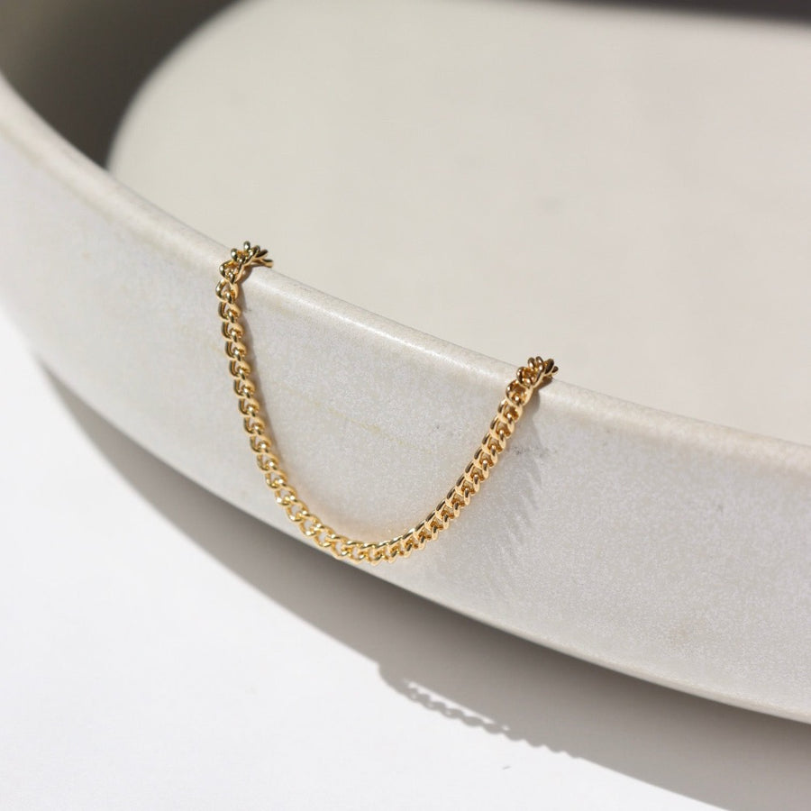 14k gold fill La Mer Anklet laid on a white plate in the sunlight.