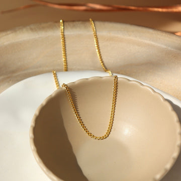14k gold fill La Mer Chain set in a tan jewelry plate in the sunlight. - Token Jewelry
