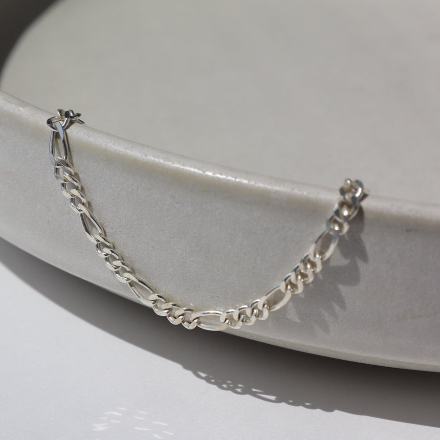 925 Sterling silver Gigi Anklet laid on a gray plate in the sunlight.