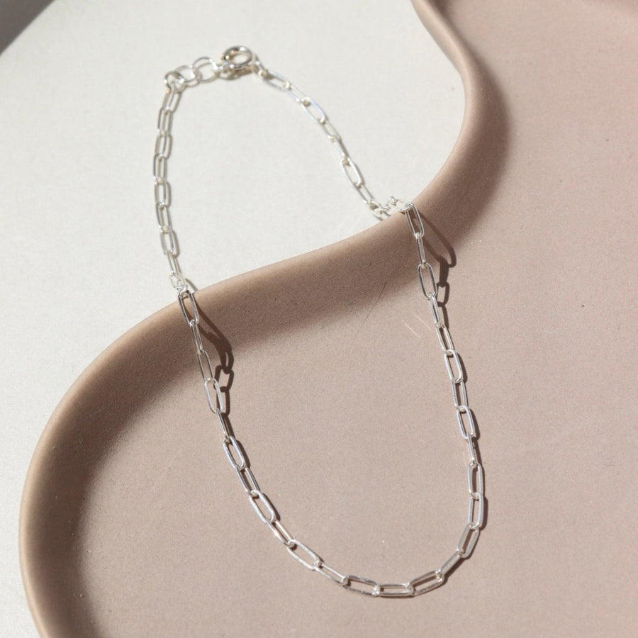 925 Sterling silver Narrow Link Anklet laid on a tan plate  