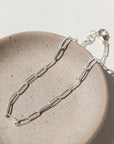 925 sterling silver piper anklet on a tan plate in the sunlight.