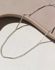 925 Sterling silver Sailor anklet laid on a tan plate in the sunlight.