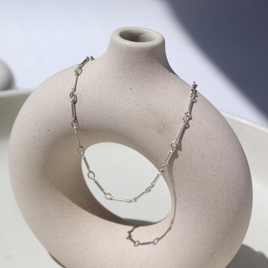 925 sterling silver Dot & Dash Anklet laid on a white pot in the sunlight.