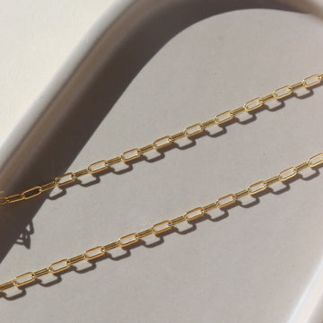 14k gold fill chain laid on a gray plate in the sunlight.
