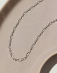 925 sterling silver Clara Anklet laid on a tan plate.