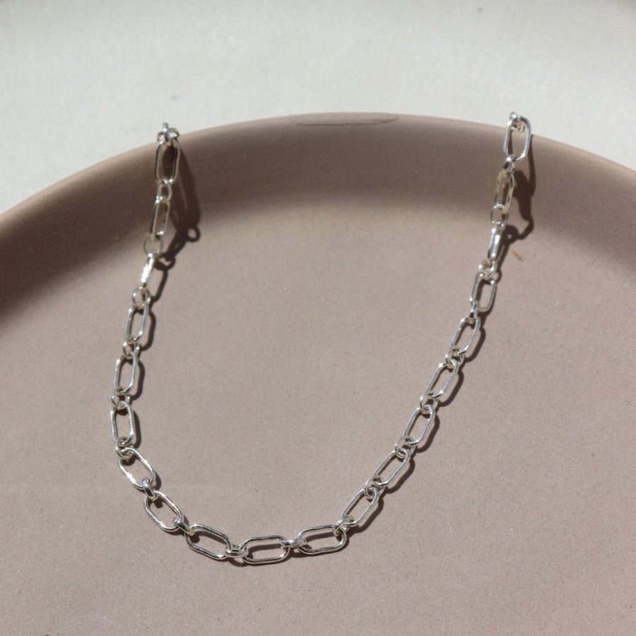 925 Sterling silver Brooklyn Anklet laid on a tan plate in the sunlight.