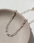 925 Sterling silver Brooklyn Anklet laid on a tan plate in the sunlight.