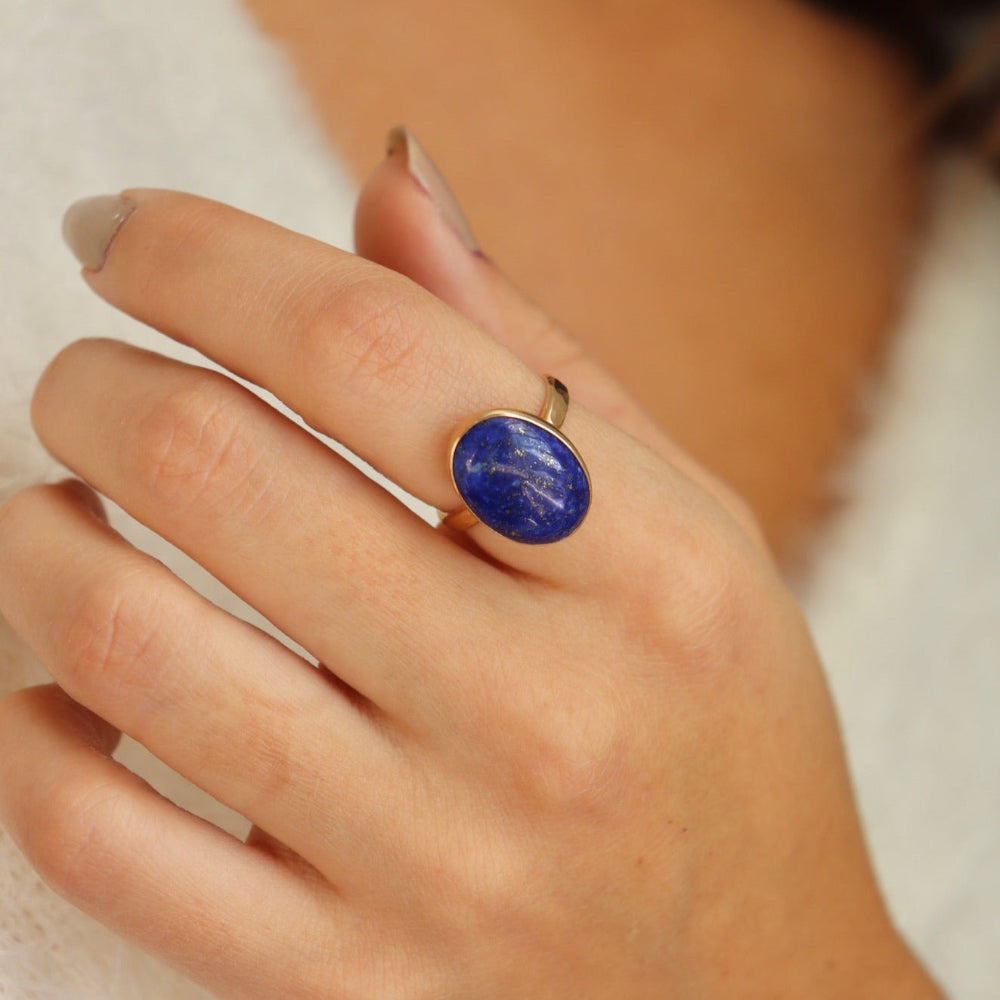 Lapis Lazuli Gemstone Ring in 14k gold fill photographed on a model. This ring features a thick gold hammered band with a 12x16mm Lapis gemstone.