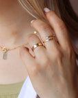 Model wearing 14k gold fill initial stamped ring in the sunlight. This ring features a hammered band that you get to customize with name or initials of your choice.