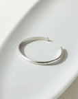 925 stacking cuff placed on a light gray plate, set in the sunlight.