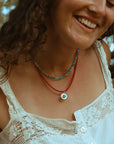model wearing turquoise and ruby beaded necklaces with round turquoise pendant