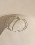 sterling silver hammered hoop earrings on a light dish