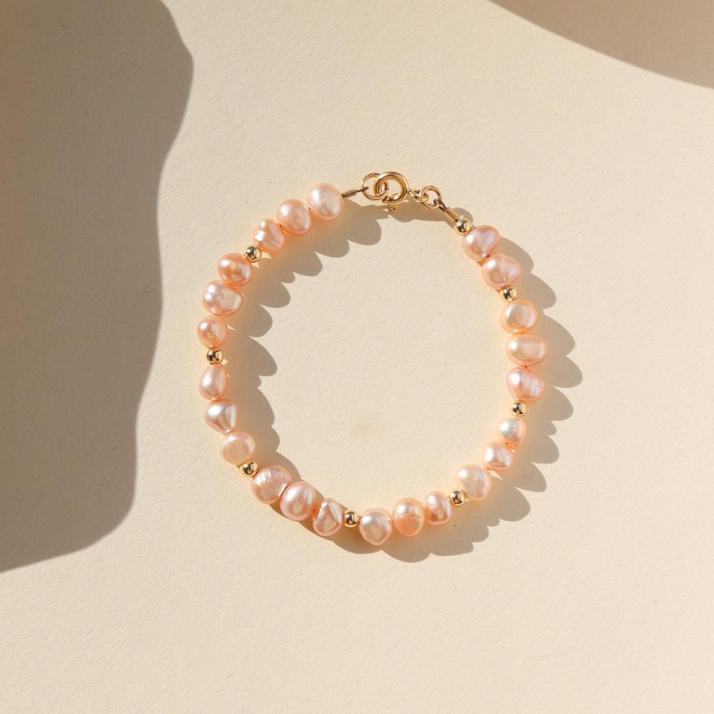 This bracelet features 29 pink pearls with a small gold bead inbetween each three pearls. This bracelet includes a gold clasp and extender.