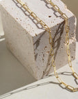14k gold fill Piper necklace laid on a stone plate in the sunlight.